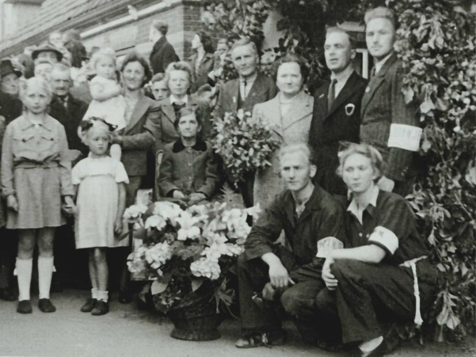 De familie Leeuw bij de terugkeer naar huis op 25 Mei 1945. Links: Jannie (met kniekousjes) en Elly. Daarachter Griet Leeuw-Roos met dochter Irene op haar arm. Rechts naast haar de verzorgster van Grietje Leeuw, de gehandicapte zus van Arend Leeuw. Voor haar: Grietje Leeuw (met zwart kraagje). Daarnaast Arend Leeuw, zijn vrouw Betje en hun zonen Arie en Joop Leeuw. Geknield: Jaap (links) en Alie (rechts) Leeuw. Foto: archief familie Leeuw.